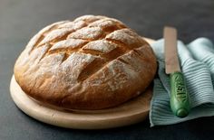 a loaf of bread sitting on top of a wooden plate next to a blue cloth