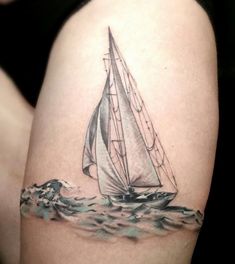 a woman's thigh with a sailboat tattoo on her left side ribcage