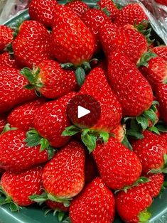 a green bowl filled with lots of ripe strawberries