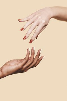 two hands reaching out towards each other with red nails on their fingertipss and one hand in the air