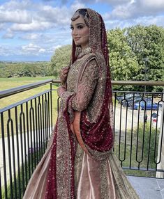 a woman in a bridal gown standing on a balcony looking off into the distance