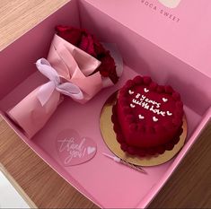 a heart shaped cake in a pink box with a rose on top and a small gift bag next to it