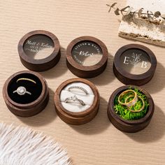 six wooden ring boxes with wedding rings in them and their names engraved on the lids