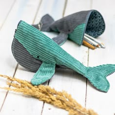 a knitted whale toy sitting on top of a wooden floor next to some scissors