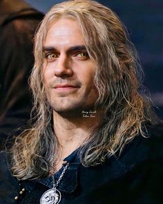 a man with long hair and piercings on his face is looking at the camera