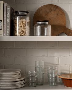 the shelves are filled with dishes, glasses and other kitchen items on it's shelf