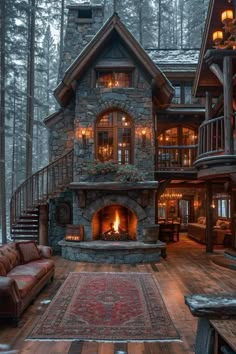 a large stone fireplace in the middle of a wooden floored living room with stairs leading up to it