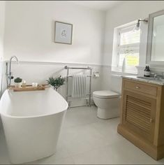 a large white bathtub sitting next to a toilet in a bathroom under a window