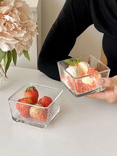 a person sitting at a table with some fruit in small bowls on the table next to them