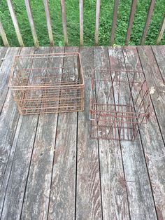 two rusty metal baskets sitting on top of a wooden deck next to eachother