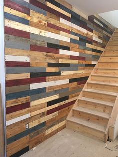 a staircase made out of wooden planks next to a wall with multicolored boards on it