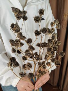 a person is holding a bunch of dried flowers in their hands and wearing a white hoodie