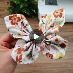 a hand holding a flower on top of a wooden table