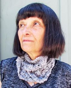 an older woman wearing a gray sweater and scarf