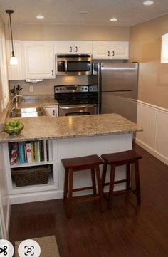 a kitchen with two stools next to an island