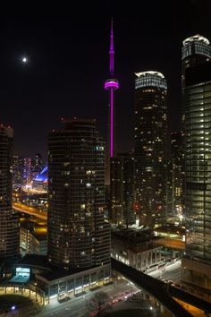 the city skyline is lit up at night with bright lights and skyscrapers in the background