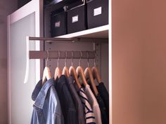 an organized closet with clothes hanging on hangers