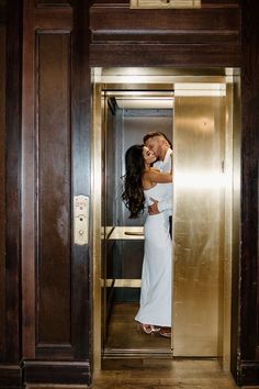 a bride and groom kissing in an elevator at their wedding reception, with the doors open