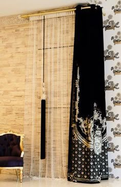 a living room filled with furniture next to a wall covered in bamboo panels and curtains