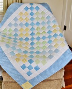 a blue and yellow quilt sitting on top of a chair