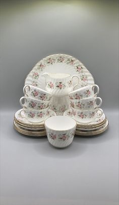 a white and pink flowered china dinner set with matching saucers, cups and saucers