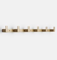 the brass coat rack has five pegs on each side and is mounted to the wall