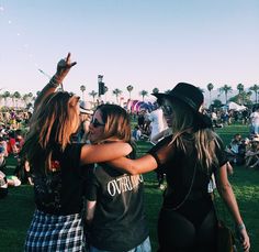 two young women standing next to each other in front of a crowd at a music festival