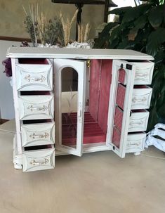 an antique white jewelry cabinet with drawers