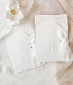 the wedding stationery is laid out on top of white linens with a flower