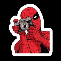 a person holding a camera in front of their face and wearing a spider - man mask