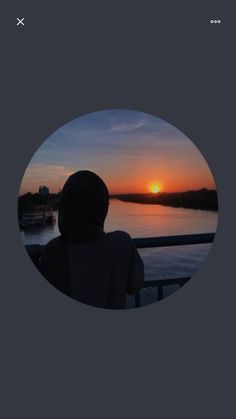 a person looking out over the water at sunset with an orange sun in the distance