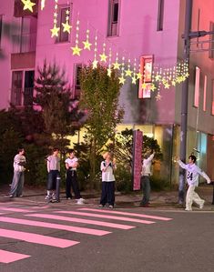 people are standing on the street in front of some buildings with stars hanging from them