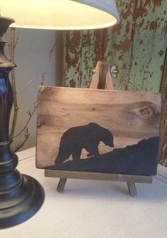 a wooden sign with an image of a bear on it next to a lamp shade