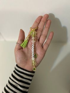 a person's hand holding a tasseled bracelet