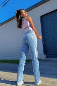 a woman in high waisted jeans is posing for the camera