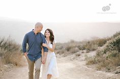 a man and woman walking down a dirt road