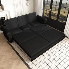 a black couch sitting on top of a hard wood floor