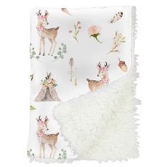 a blanket with deers and flowers on it, next to a white throw pillow