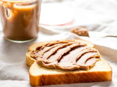 peanut butter and jelly sandwich on a white napkin next to a jar of peanut butter