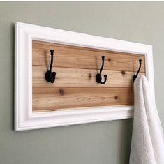 a towel hanging on a wall next to two hooks and a white frame with black handles