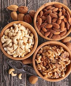 three bowls filled with nuts on top of a wooden table