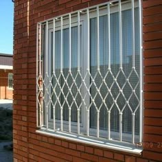 a red brick building with a white window and bars on the windowsill, in front of a parking lot