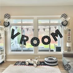 a room decorated for a race car themed birthday party with balloons and streamers on the windows