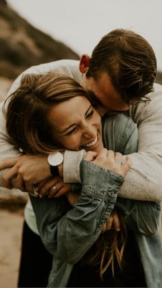 two people hugging each other on the beach