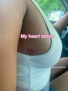 a woman with a small heart tattoo on her chest in the back seat of a car