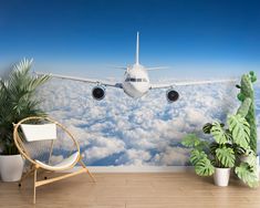 an airplane is flying over the clouds in this room with plants and a wicker chair