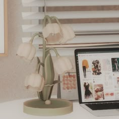 a laptop computer sitting on top of a desk next to a flower pot and lamp