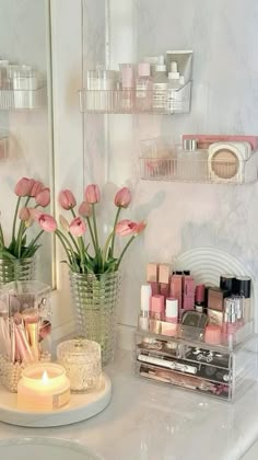 a bathroom vanity with pink flowers and makeup on it's counter top next to a mirror