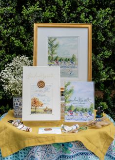 a table topped with pictures and cards on top of a yellow cloth