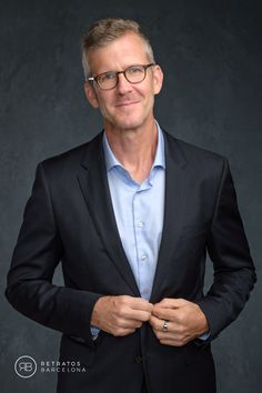 a man in a suit and glasses is posing for a photo with his hands on his chest